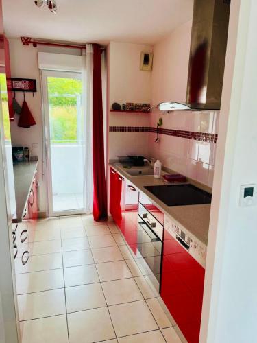une cuisine avec des armoires rouges et une grande fenêtre dans l'établissement T3 St Jean de Luz, à Saint-Jean-de-Luz