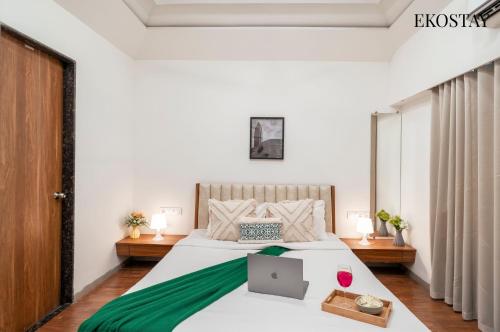 a bedroom with a bed with a laptop on it at EKOSTAY - Golden Oasis in Alibaug