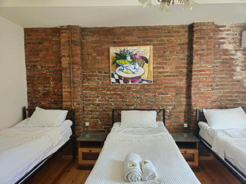 two beds in a room with a brick wall at Boutique Hotel Verdzi in Kutaisi