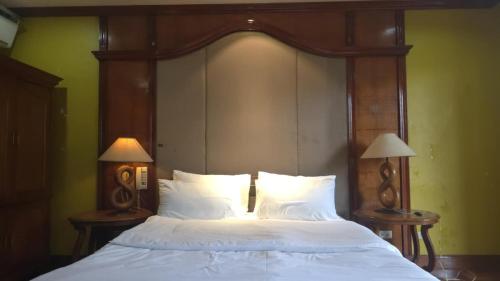 a bed with a wooden head board and two lamps at Hassan Sisters' EnSuites in Manila