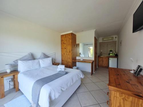 a bedroom with a large white bed and a kitchen at East London - Airport - Birder Paradise Units in Gulu