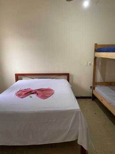 a bedroom with a white bed with a red bow on it at Hotel econômico no centro para 4 pessoas in Sete Lagoas