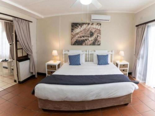a bedroom with a large bed with blue pillows at Gracelands Beach Lodge in Ramsgate