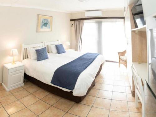a bedroom with a large bed with blue pillows at Gracelands Beach Lodge in Ramsgate