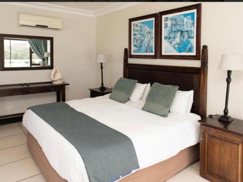 a bedroom with a large white bed with green pillows at Gracelands Beach Lodge in Ramsgate