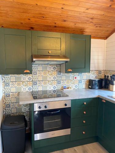 a kitchen with green cabinets and a stove top oven at Otter 1 HuntersMoon-Warminster-Longleat-Wiltshire in Warminster