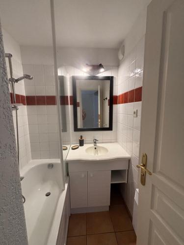 a bathroom with a sink and a tub and a mirror at Appartement de vacance in Uhart-Cize