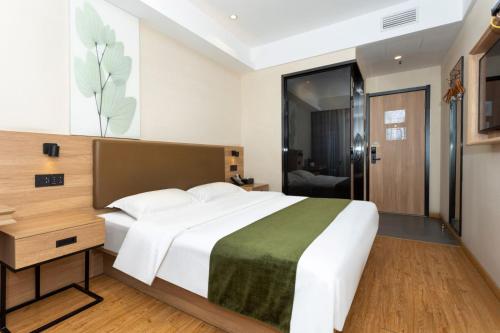 a bedroom with a large white bed and a glass door at GreenTree Inn in Shanghai