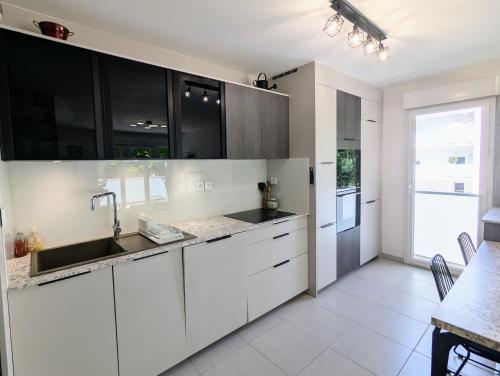 a kitchen with white cabinets and a sink at T3 neuf Baignots proche Thermes, centre, parking in Dax