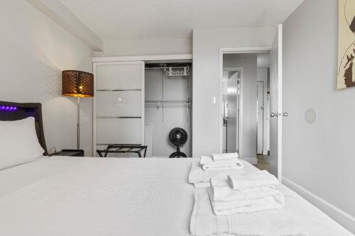 a bedroom with a large white bed with two white towels at Suite near Downtown, BMO, Stampede, Free Parking in Calgary