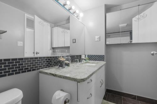 a white bathroom with a sink and a toilet at Suite near Downtown, BMO, Stampede, Free Parking in Calgary