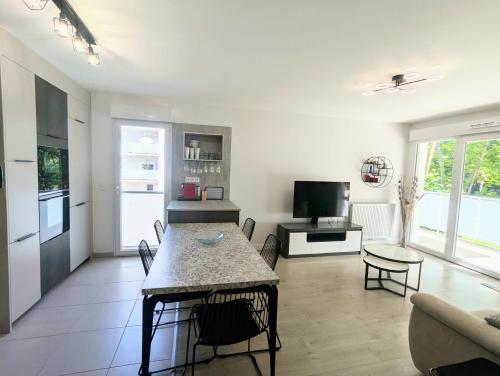 Il comprend un salon avec une table à manger et une cuisine. dans l'établissement T3 neuf Baignots proche Thermes, centre , Calme, confort, à Dax