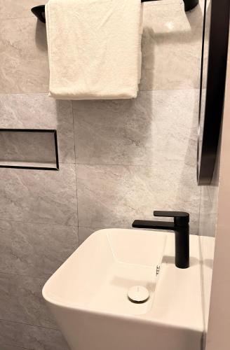 a white sink with a black faucet in a bathroom at Iris by kisali in Dar es Salaam