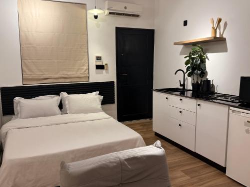 a bedroom with a large white bed and a kitchen at Iris by kisali in Dar es Salaam