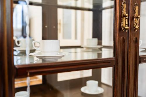 a glass counter with cups and saucers on it at Spa Jewel - Stylish Flat in the Center! with Sauna in Karlovy Vary