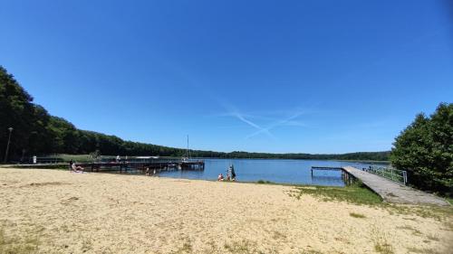 a beach with people sitting on the sand and a dock at Domek letniskowy brązowy -całoroczny in Stegers