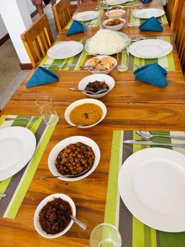 a wooden table topped with plates and bowls of food at Levi's Tourist – Anuradhapura in Anuradhapura
