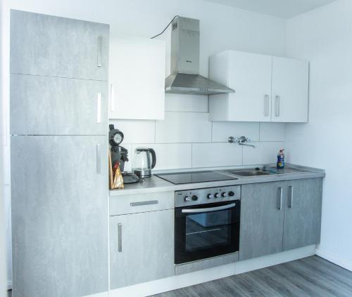 a kitchen with stainless steel appliances and white cabinets at Wohnung Smart-TV, Küche, Balkon in Emden