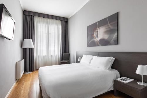 a hotel room with a white bed and a window at Palace Suite in Trieste