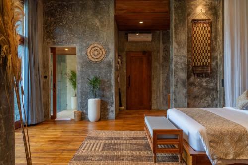 a bedroom with a bed and a wooden floor at The Lumbung Jaya Resort in Tegalalang