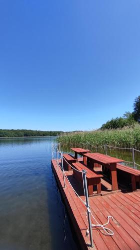 a dock with picnic tables on the water at Domek letniskowy - czerwony całoroczny in Stegers
