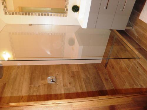 a glass floor in a bathroom with a toilet at Aqualiget-Apartmanház E-Car plug-in point Szeged in Szeged