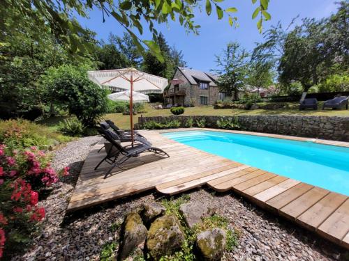 a wooden deck next to a swimming pool with an umbrella at Chateauret in Espagnac