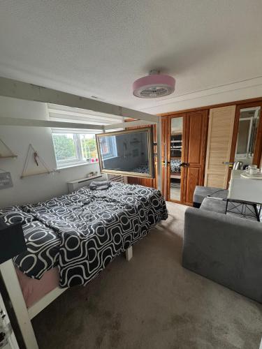 a bedroom with a bed and a couch and a television at Room 3 minute drive from Luton Airport in Luton