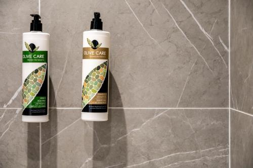 two bottles of olivegrass hair products sitting on a wall at Unicos City Suites in Kos Town