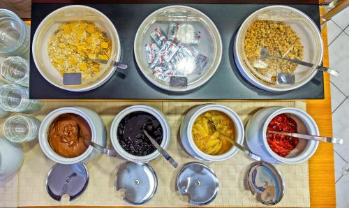 a bunch of bowls of food on a table with spoons at Hotel Nereides in Patitiri
