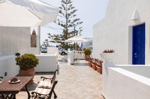 a patio with chairs and tables and a blue door at Villa Happening in Imerovigli