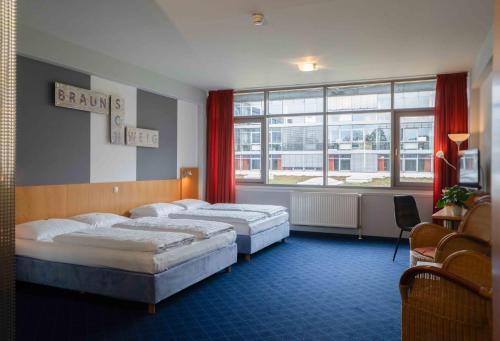 a hotel room with three beds and a window at Plaza Inn Braunschweig City Nord in Braunschweig