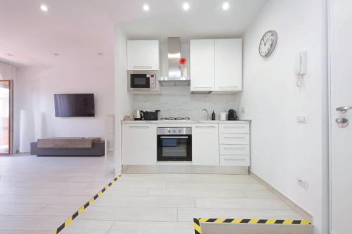 a kitchen with white cabinets and a black and yellow stripe on the floor at Attico con balcone - Mare e Comfort in Lido di Ostia