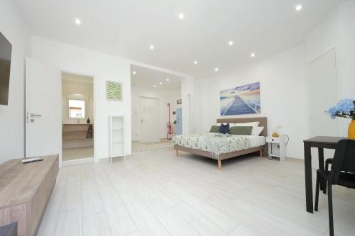 a large white room with a bed and a table at Attico con balcone - Mare e Comfort in Lido di Ostia