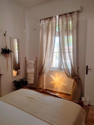 a bedroom with a bed and a window with curtains at Maroudas Traditional Guest House in Vathi