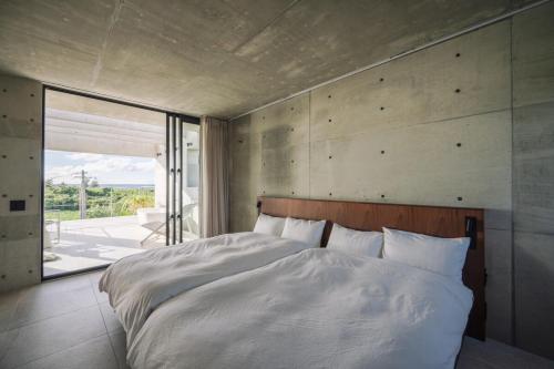 a bedroom with a large bed and a large window at villa irifi 夕陽を望むヴィラ in Miyako Island