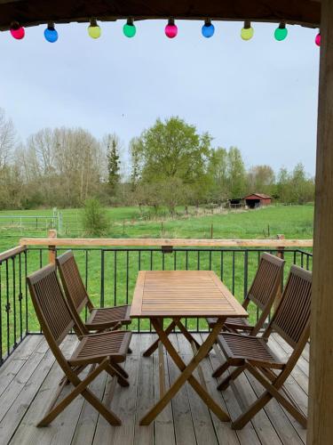 a wooden table and two chairs on a deck at Roulotte - Au pré du chêne 