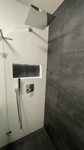 a bathroom with a shower with a black and white wall at Apartmán pod Radhoštěm in Frenštát pod Radhoštěm