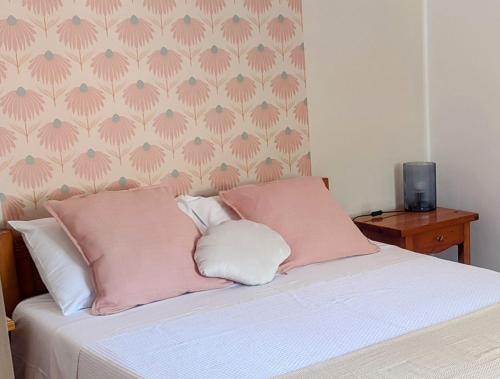 a bed with pink and white pillows and a wall at Maroudas Traditional Guest House in Vathi, Ithaka