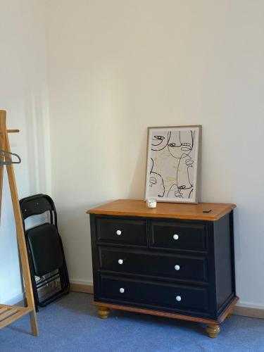 a black dresser with a picture on top of it at Grand T2 en centre-ville quartier historique in Fontenay-le-Comte