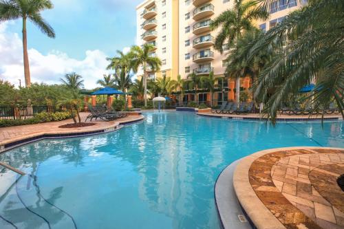 a large swimming pool with palm trees in front of a building at Wyndham Palm-Aire Studio Apartment with Resort Access in Pompano Beach