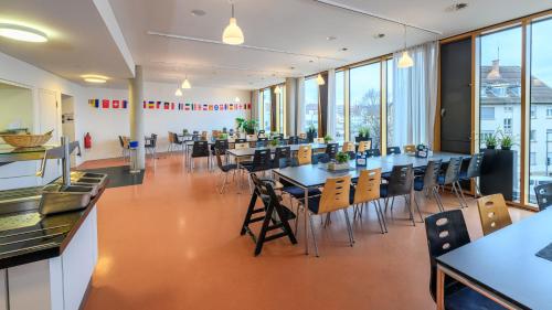a restaurant with tables and chairs and windows at Jugendherberge Stuttgart Neckarpark in Stuttgart
