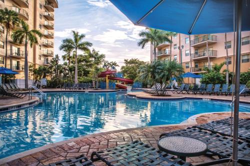 a swimming pool at a resort with chairs and an umbrella at Wyndham Palm-Aire 1BR Apartment with Resort Access in Pompano Beach
