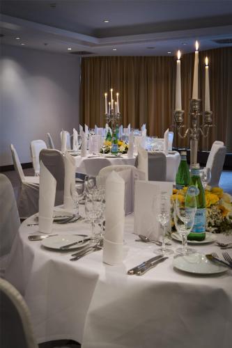 a dining room with white tables and white chairs at Park Inn by Radisson Lübeck in Lübeck