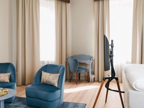 a hotel room with two blue chairs and a bed at Hotel Ruth, WorldHotels Crafted in Stockholm