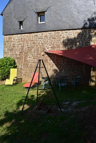 a swing set in front of a brick building at Gîte dans la campagne Bretonne - Le jardin de Devant in Villamée