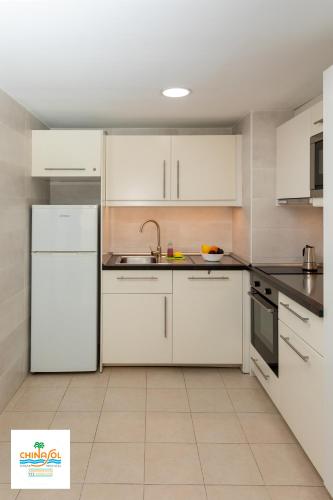 a white kitchen with white cabinets and appliances at Apartamentos Chinasol in Almuñécar