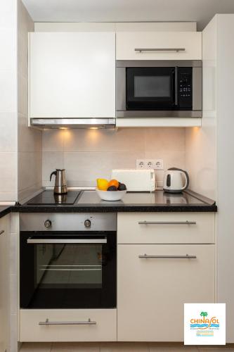 a kitchen with a microwave and a stove top oven at Apartamentos Chinasol in Almuñécar