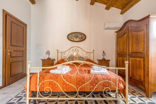 a bedroom with a bed with an orange bedspread at Arcaloro Resort Rooms in SantʼAngelo di Brolo