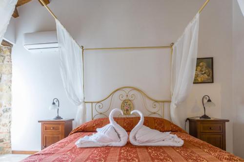 two white swans are sitting on a bed at Arcaloro Resort Rooms in SantʼAngelo di Brolo